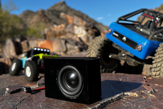 The Super Single on a rock slab with a blue RC crawler and a second rig out of focus behind it. 1/10 scale.