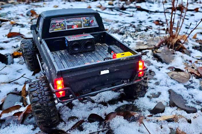 The Double in the bed of a black RC pickup parked on snow with its tail lights lit. 1/24, 1/18 and 1/10 scale.