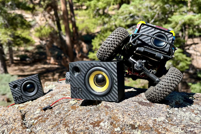 Two Supreme Single speakers on granite in front of a black comp crawler climbing behind them. 1/10 scale.