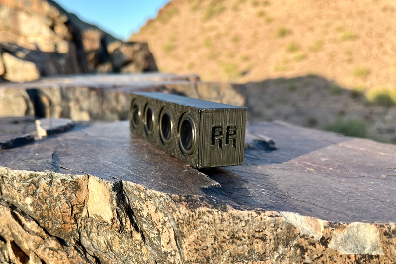 The Quad angled across a rock slab with the RR logo stamped between the drivers. 1/10 scale.