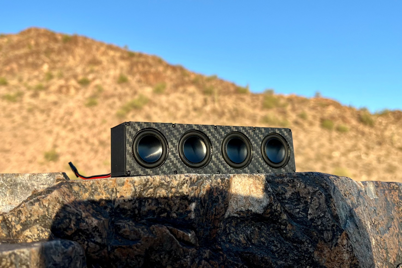 The Quad on a rock shelf with a desert hillside behind and the receiver lead trailing off the edge. 1/10 scale.