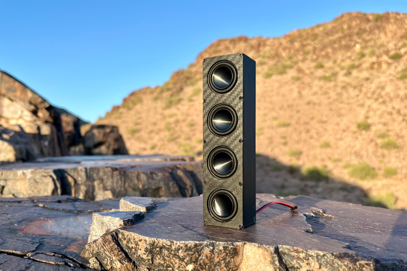 The Quad stood upright on a rock with its receiver lead coiled at the base. 1/10 scale RC speaker.