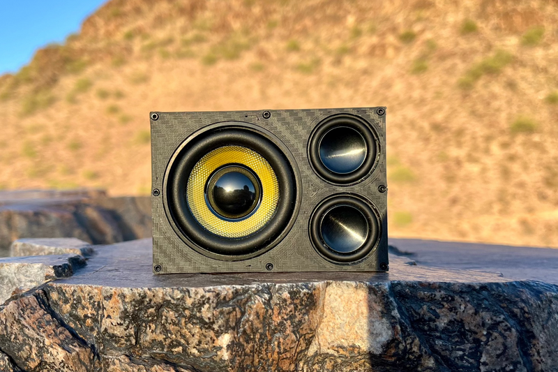 The Overkill on desert rock, one 52 mm driver with a yellow cone and two 1-inch drivers stacked beside it. 1/10 scale RC speaker.