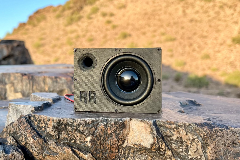 The Supreme Single on desert rock, one 52 mm driver with a black cone and the RR logo on the face. 1/10 scale RC speaker.