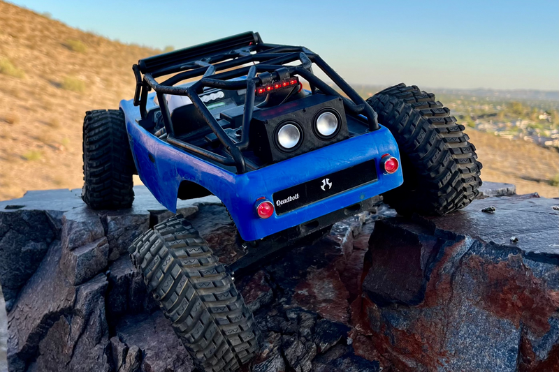 The Double mounted at the back of a blue RC crawler's cage with the drivers facing rearward, parked on rock at dusk. 1/24, 1/18 and 1/10 scale.