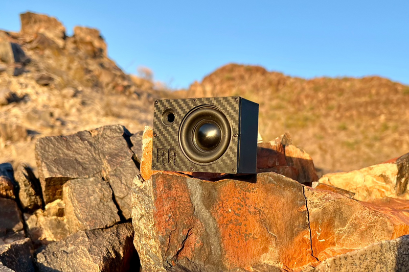 The Super Single angled on broken desert rock, yellow cone catching the light and the RR logo on the face. 1/10 scale.