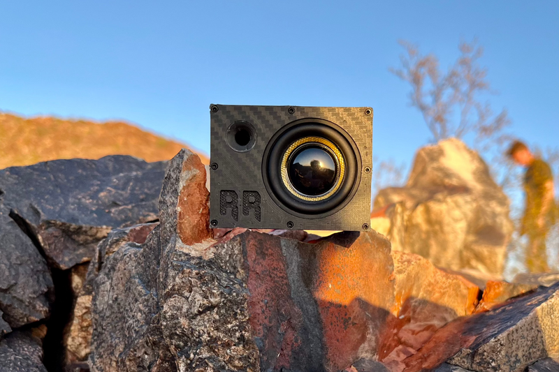 The Super Single wedged between desert rocks with the yellow-cone driver facing out. 1/10 scale RC speaker.