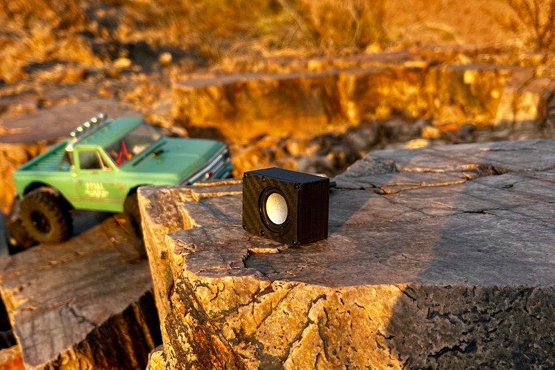 The Micro Single on a rock ledge at sunset with a green Chevrolet-bodied RC pickup parked behind it. 1/24 and 1/18 scale.
