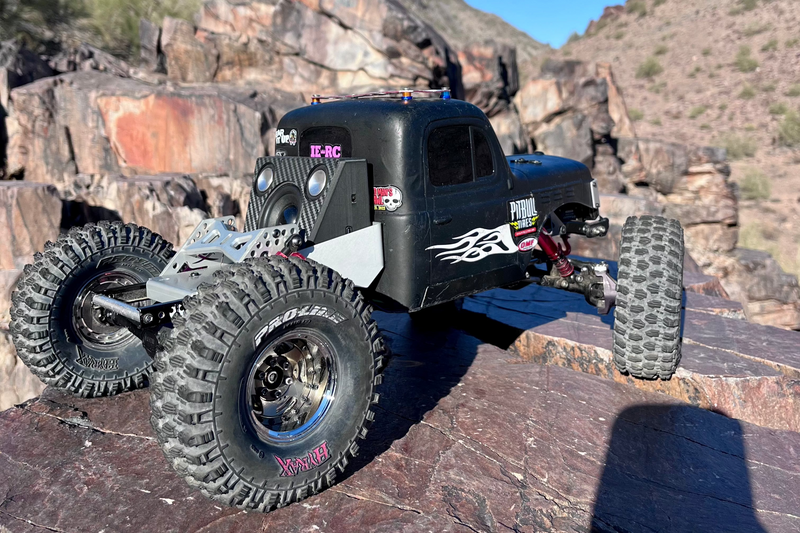 Side view of a black comp crawler on rock with The Overkill for Hardline Bed mounted at the front. 1/10 scale.