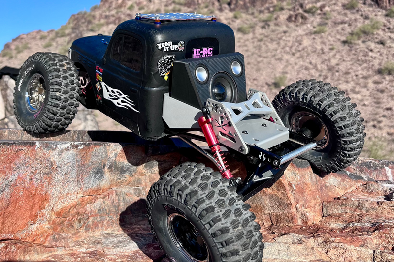 The Overkill for Hardline Bed on the front of a black comp crawler, three-quarter view on desert rock. 1/10 scale.
