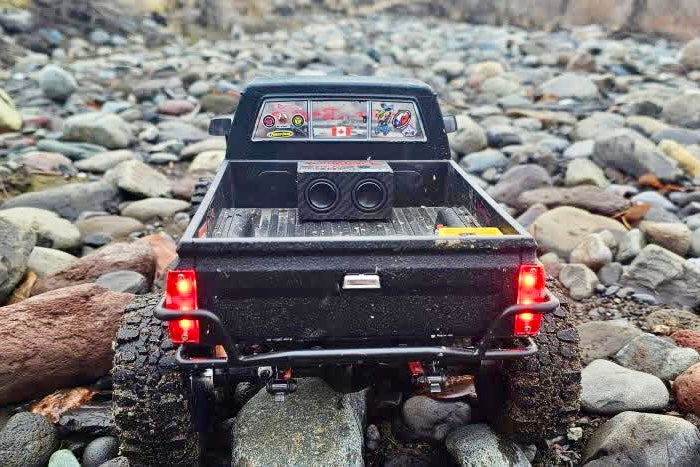 The Double sitting in the bed of a black RC pickup on river rock, both drivers facing the camera. 1/24, 1/18 and 1/10 scale.