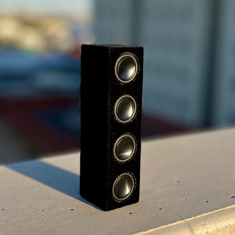 The Quad in black suede wrap stood on end on concrete, drivers running top to bottom. 1/10 scale.