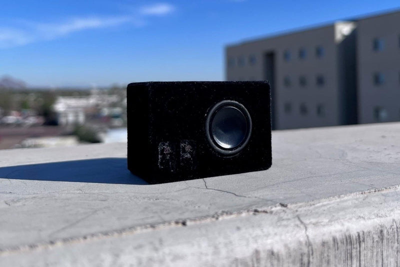 The Mini in black suede wrap on a concrete ledge with buildings behind. 1/24 and 1/18 scale RC speaker.