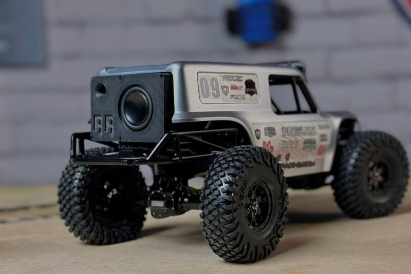 The Mini mounted in the roll cage of a white-bodied comp crawler, driver facing forward. 1/24 and 1/18 scale.