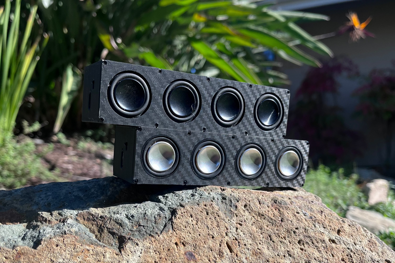 Two Quad speakers leaning together on a garden rock, eight drivers between them. 1/10 scale.