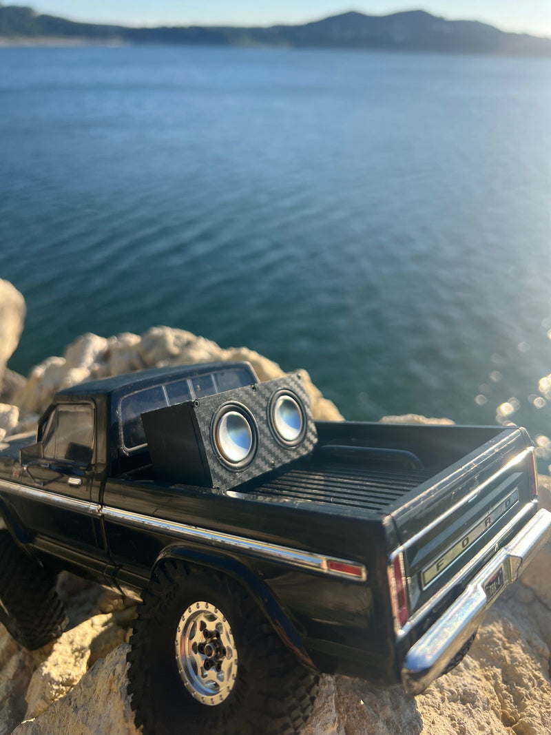 The Double mounted in the bed of a black RC pickup on limestone above a lake, both drivers facing out. 1/24, 1/18 and 1/10 scale.