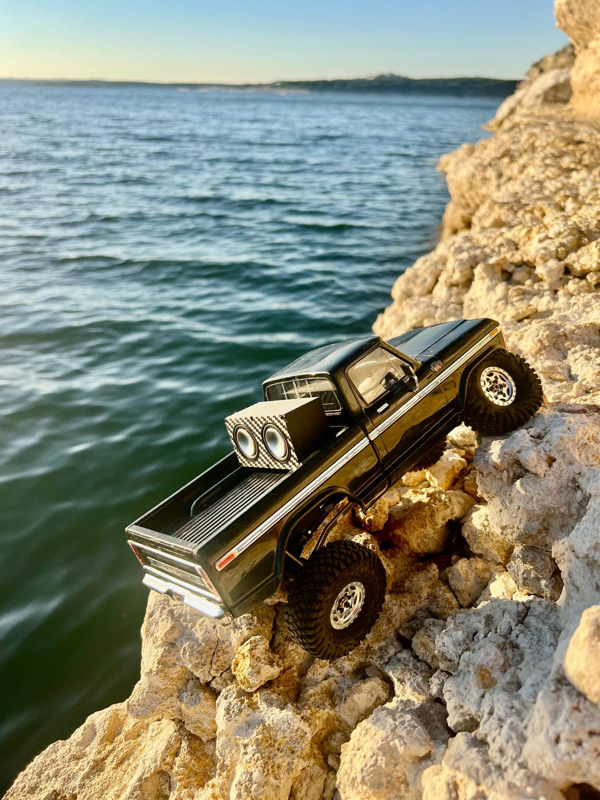 The Double in the bed of a black RC pickup climbing limestone at the water's edge, seen from above. 1/24, 1/18 and 1/10 scale.